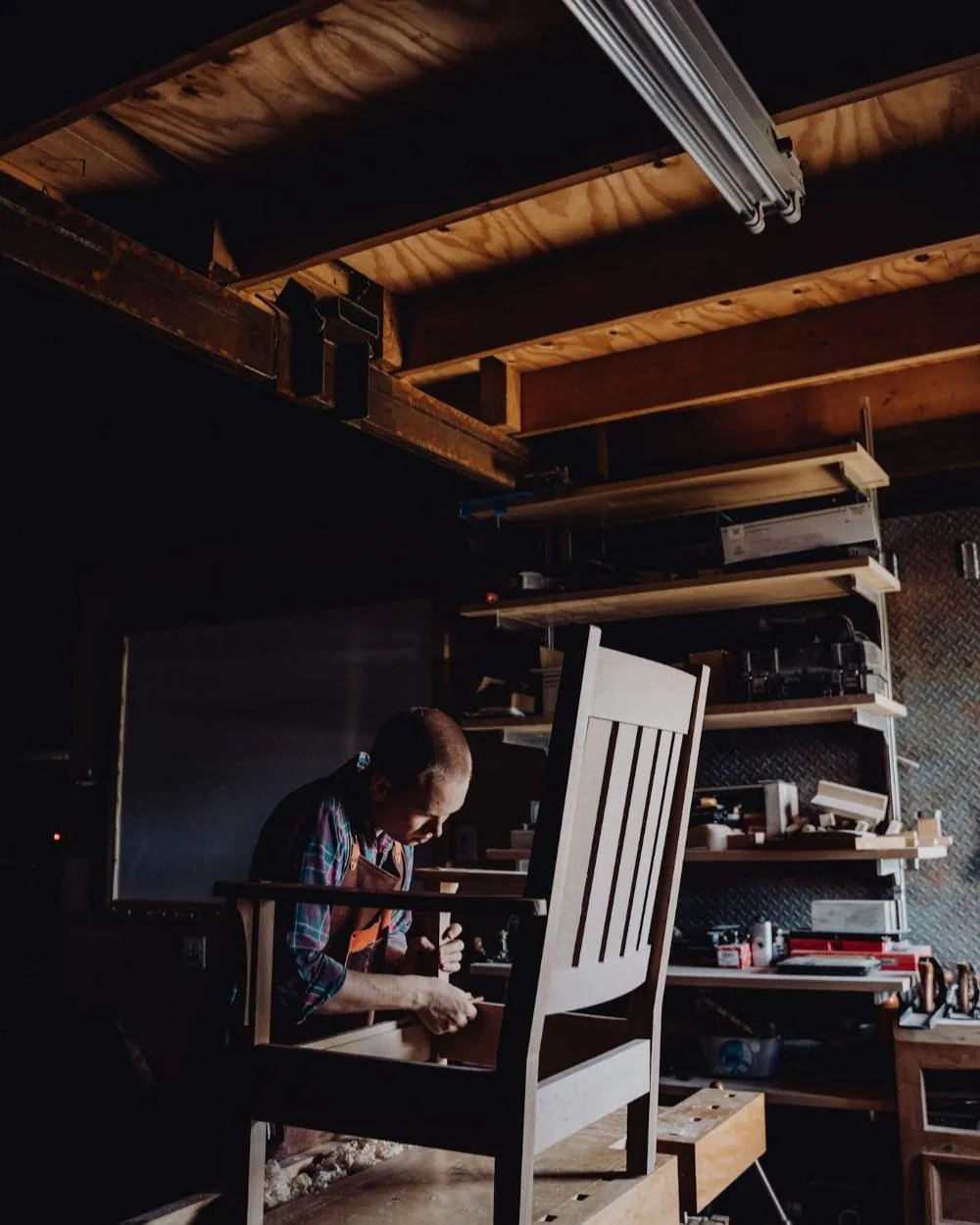 Menuisier ajustant un fauteuil en bois dans son atelier